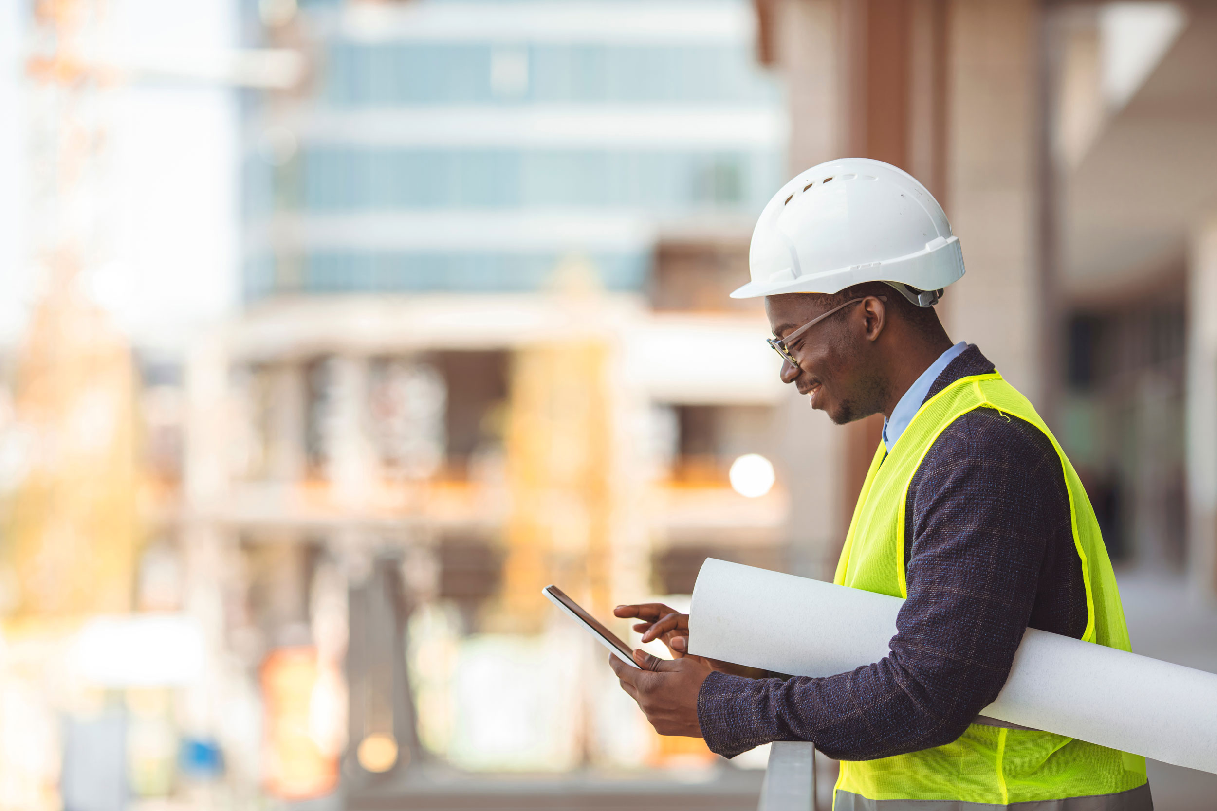 Male construction worker, wearing safeting vest and helmet interacting with mobile phone