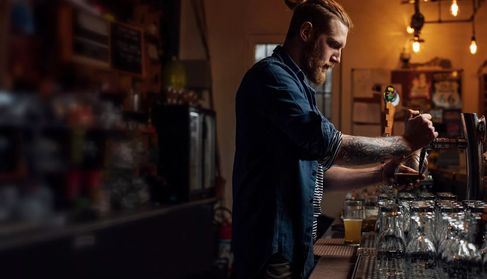 A man pours a beer in a bar environment
